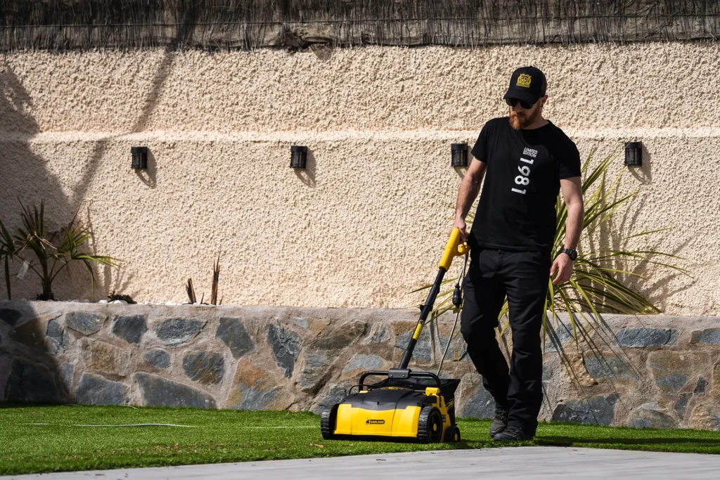Joven con gafas y gorra usando maquina Roll&Comb en cesped de piscina